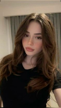Woman with long brown hair and freckles wearing a black shirt indoors