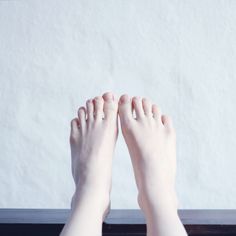 Bare feet with pale skin against a white background and dark surface