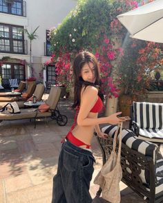 Woman in a red bikini top and loose jeans on an outdoor patio