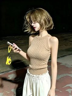 Woman with short blonde hair in a knitted top and white skirt at night