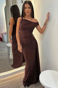 Woman in a long dark brown dress posing in front of a mirror