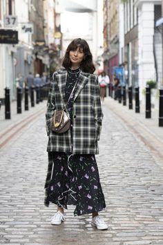 Woman in a plaid blazer and floral dress on a cobblestone street