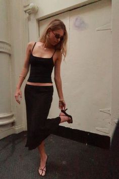 Woman in a black camisole and long skirt posing indoors