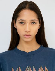 Woman with long dark hair and a blue t-shirt against a white background