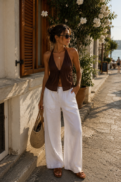 Woman in a brown halter top and white pants on a sunny street