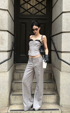 Woman in a corset top and pinstripe pants standing on stone steps
