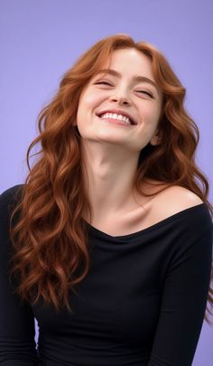 Woman with long red hair and an off-shoulder top smiling against a purple background
