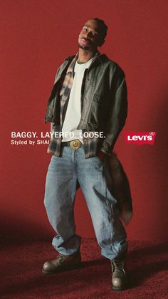 Man in a denim jacket, plaid shirt, and baggy jeans against a red background
