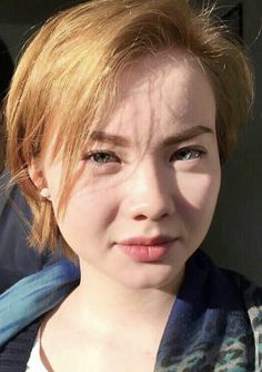 Close up portrait of a person with short blonde hair and green eyes