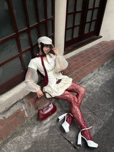 Woman in a white dress and red lace tights sitting outdoors