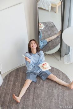 Woman in a striped shirt and shorts sitting on a rug with a cake