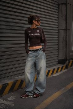 Woman in a cropped top and baggy jeans standing on a street