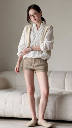 Woman in a white shirt and khaki shorts standing indoors