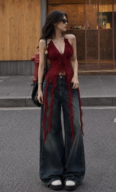 Woman with long hair and sunglasses wearing a red top and wide leg jeans on a street