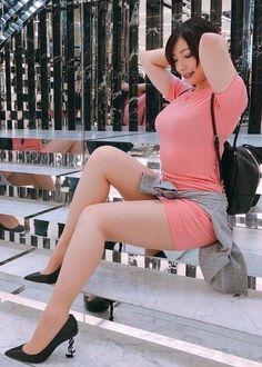 Woman in a pink dress and high heels sitting indoors