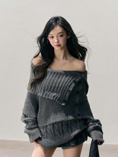 Woman with long dark hair wearing an off-shoulder dark grey sweater