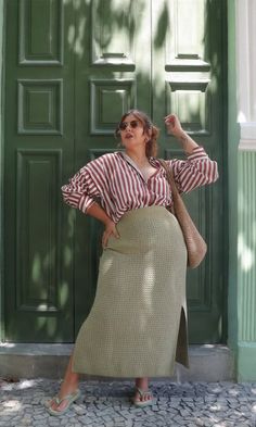 Woman in a striped shirt and long skirt posing in front of a green door