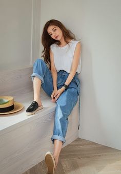 Woman with long hair wearing a white t-shirt and blue jeans sitting on stairs