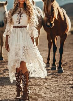 Woman in a white lace dress and cowboy boots with horses in a desert landscape