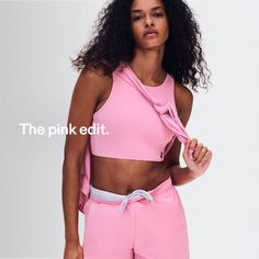 Woman in a pink sports bra and shorts with a matching top tied over her shoulder