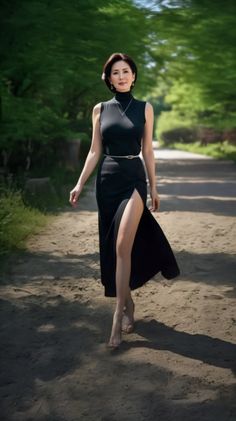 Woman in a black dress with a high slit walking barefoot on a dirt path