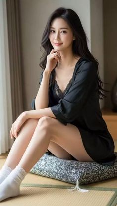 Woman with long black hair wearing a black robe with lace trim, sitting indoors