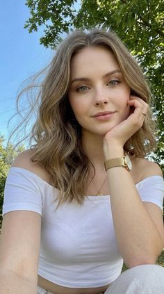 Woman with blonde wavy hair wearing an off-shoulder top outdoors