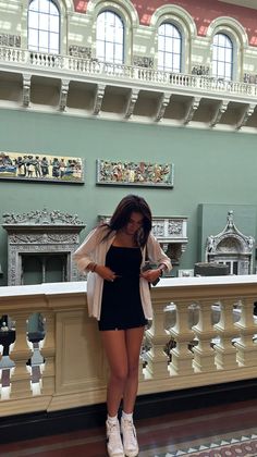 Woman in a black dress and white shirt standing in a museum