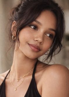 Woman with dark hair and gold jewelry looking to the side