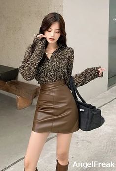 Woman in a floral shirt and brown leather skirt with a black handbag outdoors