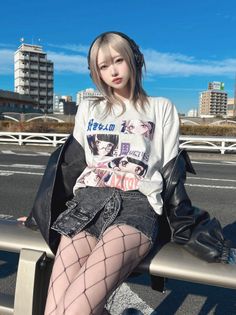 Woman with blonde hair and headphones wearing a denim skirt and fishnet stockings outdoors