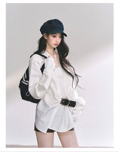 Woman with long dark hair wearing a white shirt and black cap with a backpack