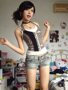 Woman in a leopard print top and denim shorts posing in a messy room
