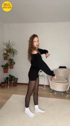 Young woman with long curly hair wearing black shorts and tights with white socks indoors