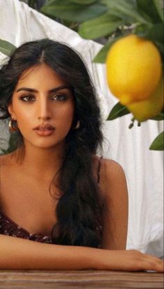 Woman with long black hair and hoop earrings outdoors with lemons