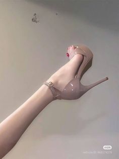 A bare leg with red nail polish wearing a nude high heel with an ankle strap