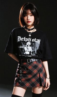 Woman with short hair wearing a choker, black t-shirt, and plaid skirt