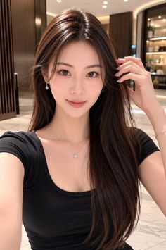 Woman with long dark hair wearing a black top and jewelry indoors