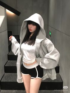 Woman in a grey hoodie and black shorts standing on stairs