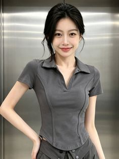 Woman with dark hair wearing a grey polo shirt, smiling at the camera