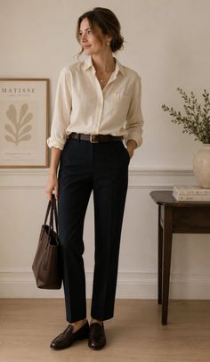 Woman in a long sleeve shirt and black pants holding a brown tote bag indoors