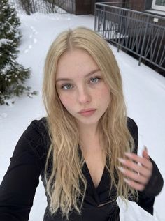 Blonde woman with freckles in a black dress outdoors in the snow