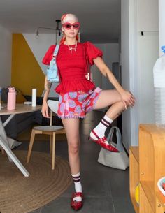 Woman in a red top and patterned shorts posing indoors