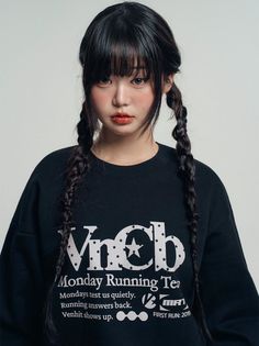 Woman with black hair in braids and bangs wearing a black sweatshirt