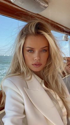 Woman with blonde hair and blue eyes in a white blazer on a boat