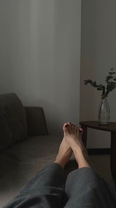Person's feet with black nail polish resting on a couch in a dimly lit room