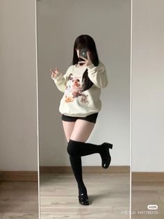 Person in an oversized sweatshirt and thigh-high socks taking a mirror selfie