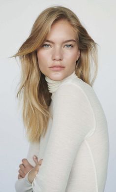Woman with blonde hair wearing a white turtleneck against a white background