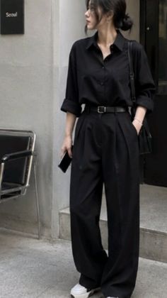 Woman in a black shirt and wide leg pants standing outdoors