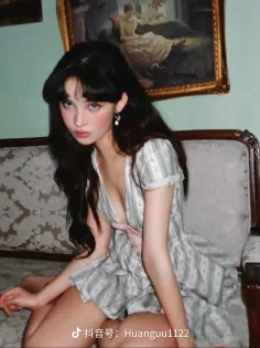 Woman with long dark hair in a striped dress sitting on a couch indoors